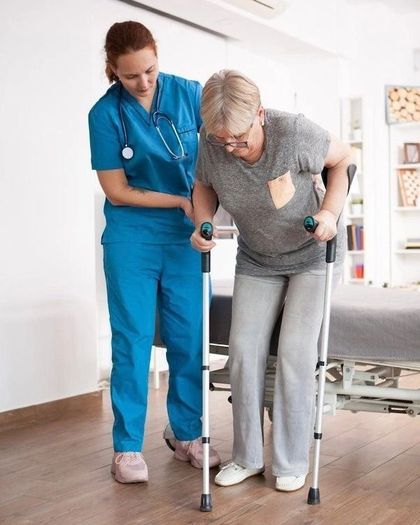 A healthcare professional assists an elderly woman with mobility aids during rehabilitation therapy, illustrating supportive care at the best German language institute in Calicut