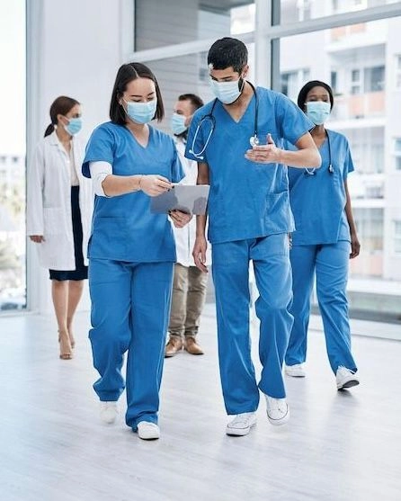 Doctors and a nurse walking in a hospital corridor discussing medical documents, symbolizing teamwork and professionalism promoting the best German language institute in Calicut